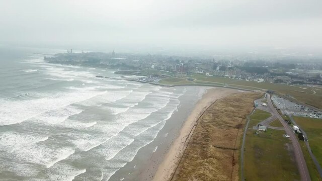 St Andrews city shrouded in fog and rough sea, Scotland. Aerial forward