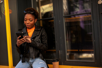 Young african woman using the phone. Beautiful woman relaxing outdoors