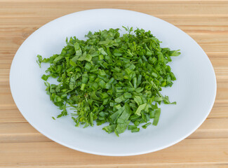 Sliced onion tails and parsley in a plate - recipe concept- in the process of cooking