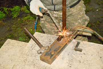 close-up - the work of a welder who welds iron parts, sparks are visible