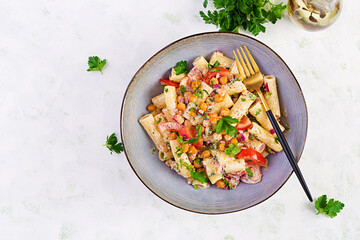 Vegetarian vegetable pasta. Pasta rigatoni with tomato, red onion, parsley and fried chickpeas with nut sauce. Vegan food. Top view, overhead
