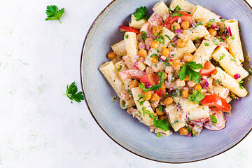 Vegetarian vegetable pasta. Pasta rigatoni with tomato, red onion, parsley and fried chickpeas with nut sauce. Vegan food. Top view, overhead