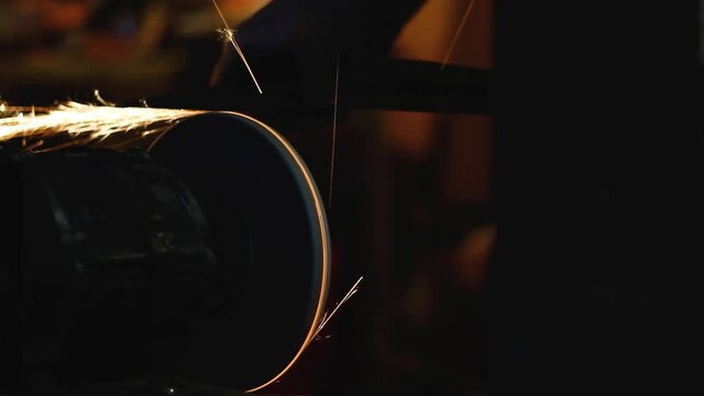 Sparks fly from the sharpening of the metal. Sharpen the axe on the rotating grinding wheel of the grinding machine.