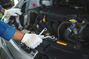 Close up hands of auto mechanic doing car service and maintenance.
