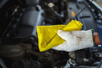 Auto mechanic in the car repair shop is checking the oil in the vehicle.