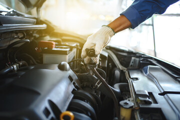 Young auto mechanic checks the water level in the radiator in the car. He was wearing white cloth...