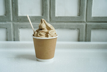Coffee soft serve ice cream. A paper cup of ice cream with coffee flavour, ice cream made of...