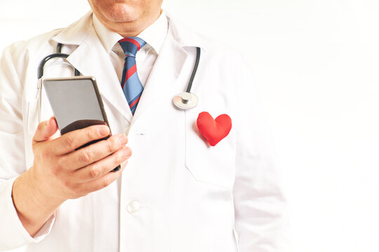 Doctor With A Heart On The Lapel Consulting The Cell Phone To View Patient Data