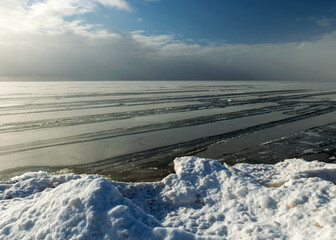 landscape by the sea, snowy pieces of ice by the sea and ice texture at sea, dunes covered with a layer of white snow