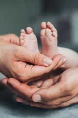 Fototapeten Newborn baby feet in parents hands © belyaaa