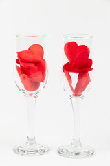 two champagne glasses with red hearts on a white wooden table. close-up. selective focus
