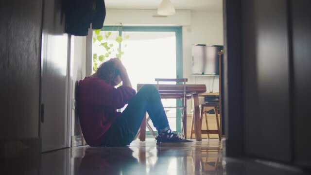 homme, triste, d&eacute;pression, personne, assis, couloir, pleure, position f&oelig;tale, pleurer, bouder, salon, maison, profile, blond, cheveux, long, boucl&eacute;e, fris&eacute;e, pull, rouge, ville, 