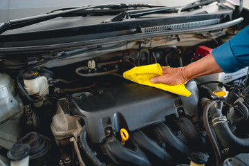 Young car mechanic cleaning the engine.