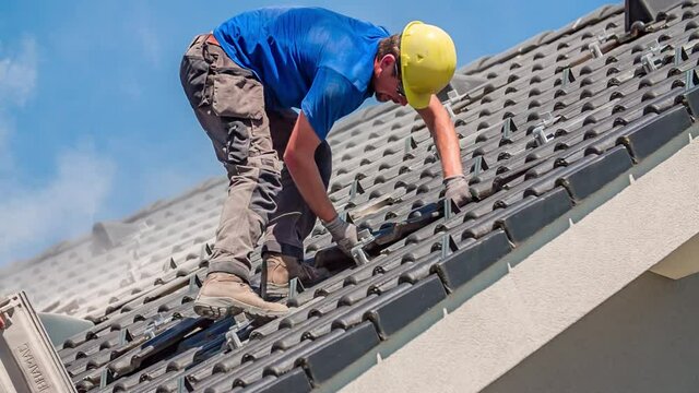 Professional roofer taking broken roof tile out, dust is everywhere