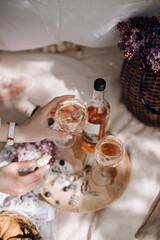 glass of rose wine in female hands top view. a transparent glass of wine and a slice of brie cheese. transparent glasses and a bottle of wine on a white picnic blanket with picnic snacks.