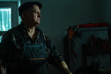 Elderly man with a hammer works in a workshop