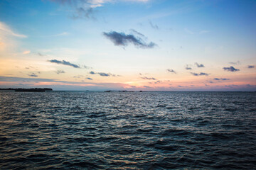 Beautiful view of sunset at sea with dramatic clouds on pink gold yellow blue sky a summer evening