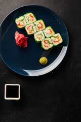 rolls in green rice paper in a blue plate on a black textured background