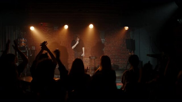 Young Caucasian male comedian finishing his stand-up monologue and leaving stage inside a small venue. Shot with ARRI Alexa Mini LF with 2x anamorphic lens