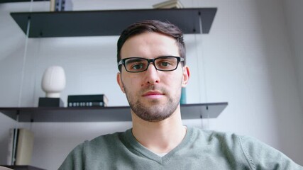 Young man listening by video link in office. Young male looking on webcam video call, slow motion