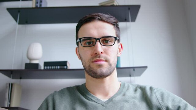 Young man listening by video link in office. Young male looking on webcam video call, slow motion