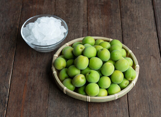 Unripe plums and rock candy on a wooden background.