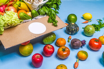 Close-up of fresh vegetables in cardboard box on the table delivered to home, donation box with supplies food for people, vegetables and fruit in cardboard box.