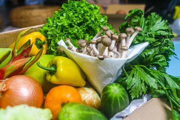 Close-up of fresh vegetables in cardboard box on the table delivered to home, donation box with supplies food for people, vegetables and fruit in cardboard box.