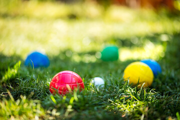 colorful plastic boules or boccia balls are lying on a green meadow