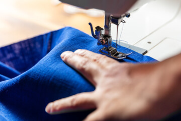 woman is working with blue linen on a sewing machine