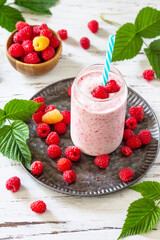 Summer cool milkshake. Raspberry protein shake in glass and fresh raspberry on a wooden table.