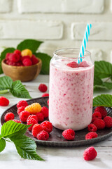 Summer cool milkshake. Raspberry protein shake in glass and fresh raspberry on a wooden table. Copy space.