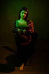 A girl in a plaid shirt with a cowboy hat illuminated by multicolored light