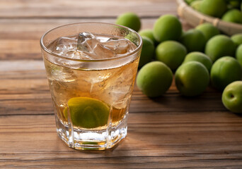 Plum wine and unripe plums on a wooden background..