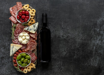 Italian antipasti or charcuterie board with wine for a holiday entertainment. Assortments of meat and cheese snacks.