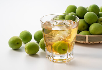 Plum wine and unripe plums on a white background.
