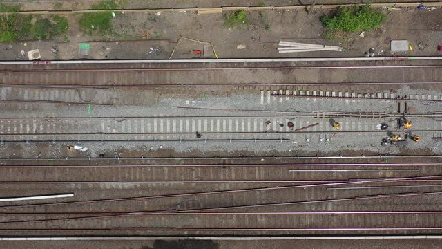 a top down aerial view directly over train tracks on a sunny day. The drone camera looking straight down, truck right along the tracks as workers repair them.