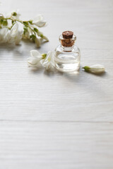 Obraz na płótnie Canvas Robinia (false acacia) essential oil (remedy, extract) bottle with fresh acacia flowers on wooden background, selective focus