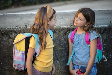 Fototapeta na wymiar Two little girls with school bags. Kids talking.