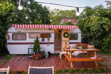 Vintage house trailer for family holidays, budget travel. On the wooden porch there is table with...