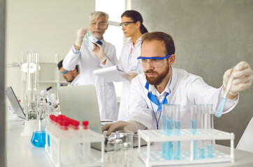 Focused male scientist in protective goggles doing medical research in laboratory, working with lab...