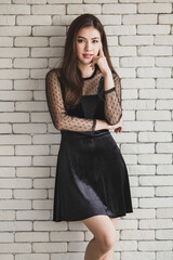 Smiling elegant woman in dress on brick wall background