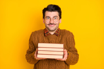 Photo of funny geek guy hold stack book shrug shoulders wear specs brown pullover isolated vivid...