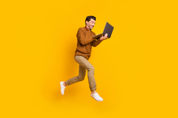 Fototapeta na wymiar Full body profile portrait of cheerful energetic man running use laptop isolated on yellow color background