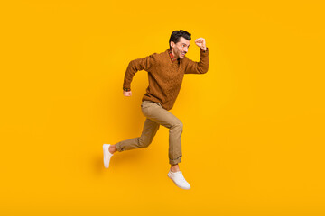 Full size profile photo of optimistic nice brunet man run wear sweater isolated on yellow background