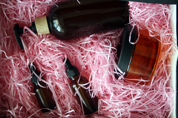 Cosmetic containers in a box with pink paper. Brown bottles. Dispenser.