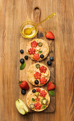 Cereals sandwiches with peanut butter with fruits and berries with honey on a wooden board, top view. Healthy tasty breakfast