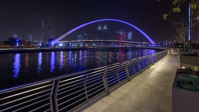 Illuminated Pedestrian Bridge over the Dubai Water Canal day to night transition timelapse which links Dubai Creek to Jumeirah Beach weaving through Deira, Downtown Dubai and Safa Park. Skyscrapers