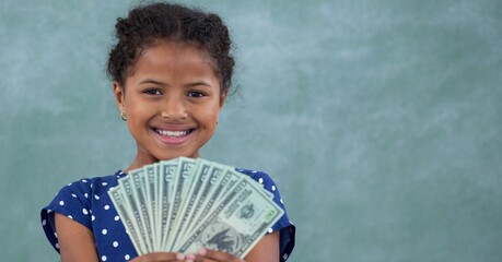 Composition of smiling girl holding american dollar bills on green background