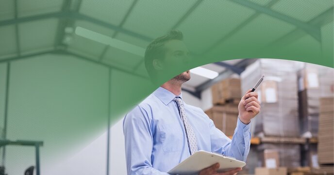 Green Technology Background Over Caucasian Supervisor Checking Stock In Warehouse